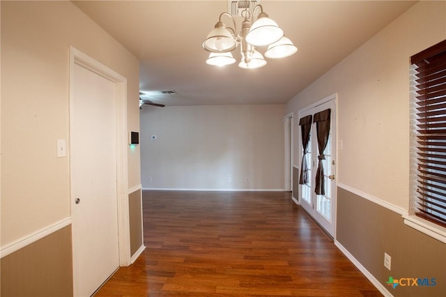 hall with a wainscoted wall, wood finished floors, visible vents, and a chandelier