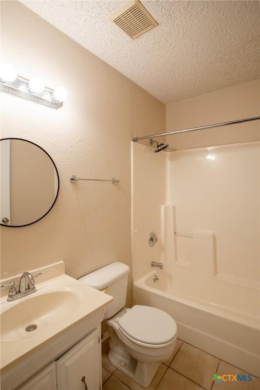 full bathroom featuring visible vents, toilet, a textured ceiling, tile patterned flooring, and vanity