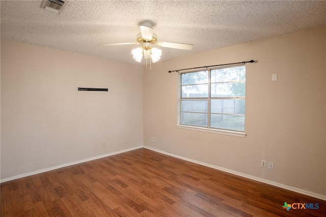 spare room with visible vents, a textured ceiling, wood finished floors, baseboards, and ceiling fan