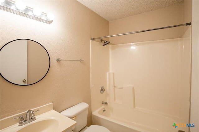 full bath featuring vanity, washtub / shower combination, a textured ceiling, toilet, and a textured wall