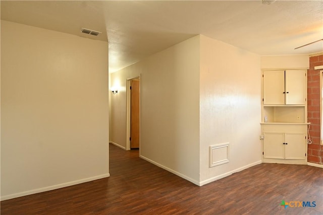 spare room with baseboards, visible vents, and dark wood-style flooring