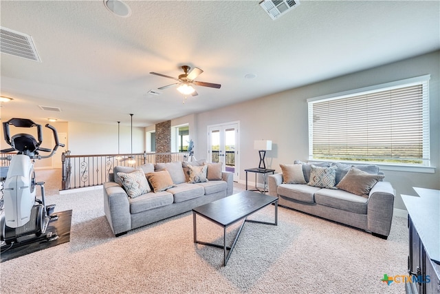 living room featuring a textured ceiling, carpet flooring, and ceiling fan