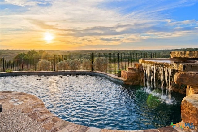 pool at dusk featuring pool water feature