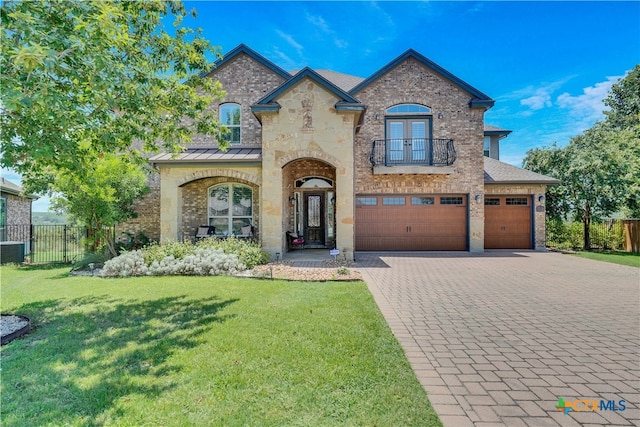 french provincial home featuring a garage, a front yard, and a balcony