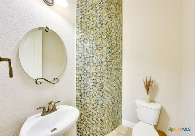 bathroom with toilet, sink, and tile patterned floors