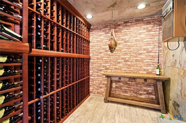 wine cellar featuring wood-type flooring and brick wall