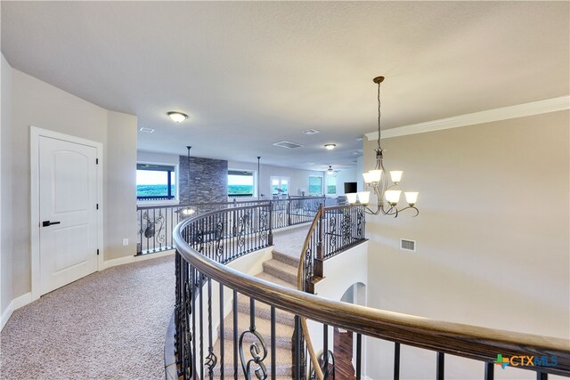 hall featuring a notable chandelier, carpet flooring, and crown molding