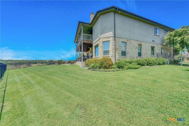 view of home's exterior featuring a lawn and a balcony