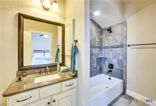 bathroom featuring vanity, tiled shower / bath, and vaulted ceiling