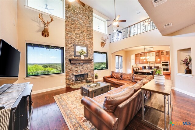 living room with a high ceiling, a fireplace, a healthy amount of sunlight, and dark hardwood / wood-style floors