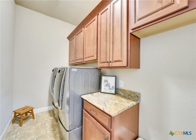 washroom featuring washing machine and dryer, cabinets, and light tile patterned flooring