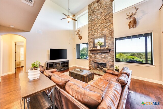 living room featuring ceiling fan, wood-type flooring, a fireplace, and high vaulted ceiling