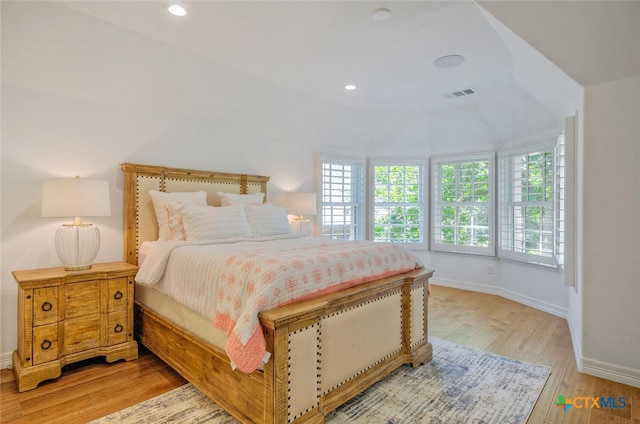 bedroom with multiple windows, vaulted ceiling, and light hardwood / wood-style floors