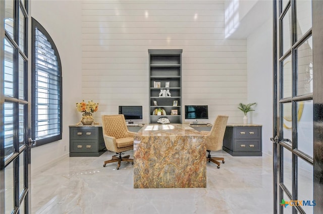 office area featuring wood walls and a high ceiling