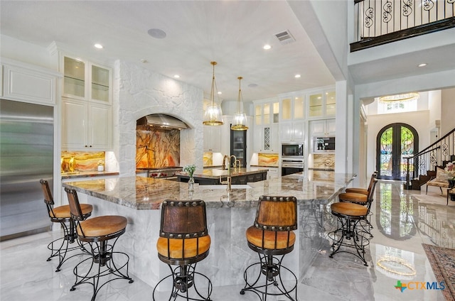 kitchen featuring a large island with sink, light stone counters, and appliances with stainless steel finishes