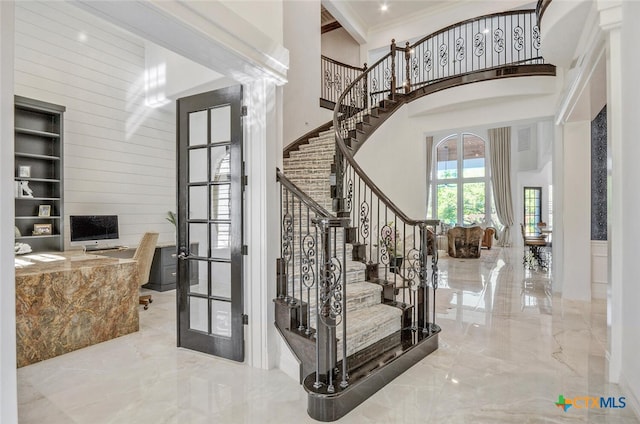 stairway featuring crown molding, french doors, and a high ceiling