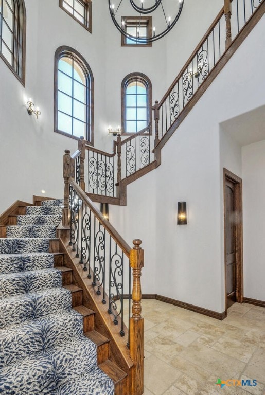 stairs featuring a high ceiling, a healthy amount of sunlight, and a notable chandelier