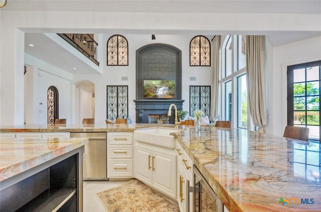 kitchen with wine cooler, sink, light stone counters, and dishwasher