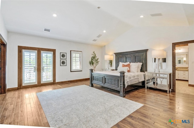 bedroom with light hardwood / wood-style flooring, vaulted ceiling, and connected bathroom