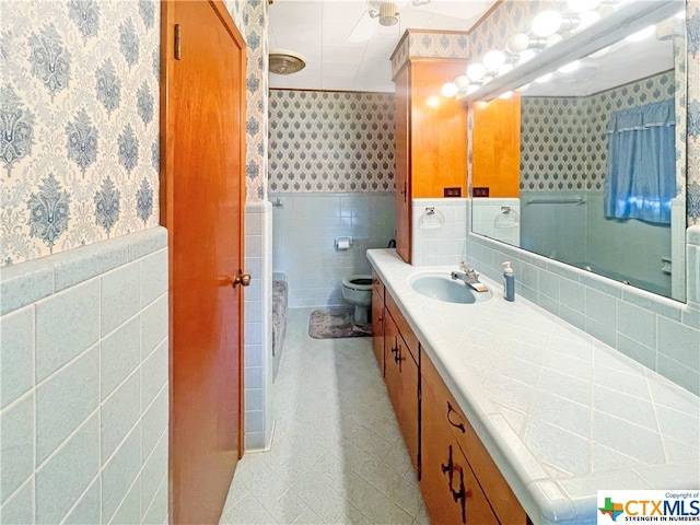 bathroom with toilet, vanity, and tile walls