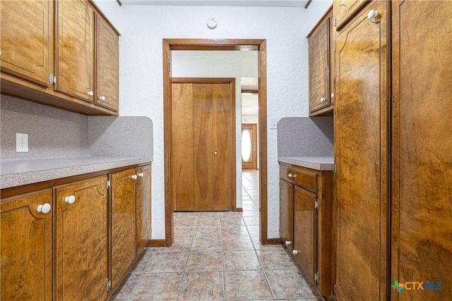 679 Royal Rd, Port Lavaca, TX 77979 - kitchen with brown cabinetry, light countertops, a textured wall, and baseboards