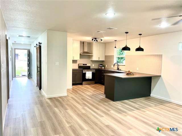 107 S 23rd St, Temple, TX 76504 - kitchen featuring stainless steel electric range oven, wall chimney exhaust hood, a peninsula, light wood-type flooring, and a textured ceiling