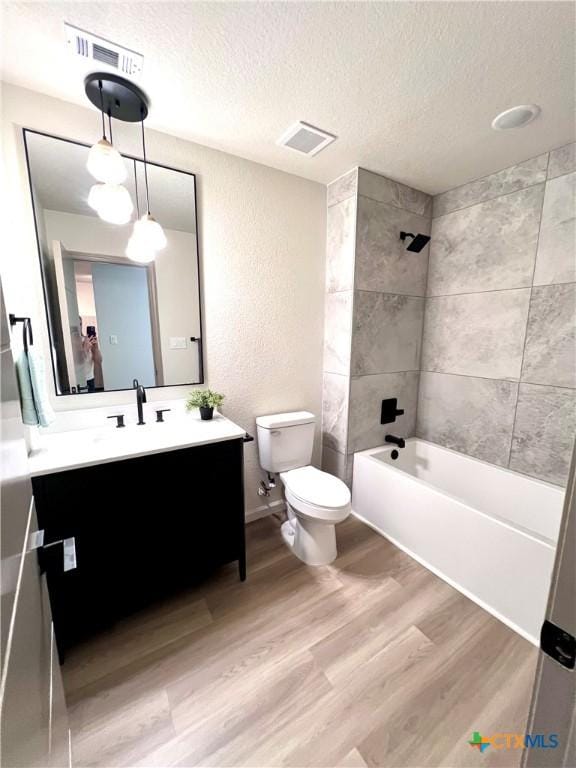 107 S 23rd St, Temple, TX 76504 - bathroom with wood finished floors, toilet, vanity, a textured ceiling, and bathing tub / shower combination