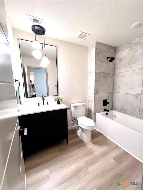 107 S 23rd St, Temple, TX 76504 - full bath featuring wood finished floors, toilet, vanity, a textured ceiling, and bathtub / shower combination