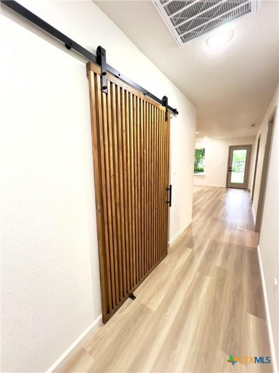 107 S 23rd St, Temple, TX 76504 - hallway featuring a barn door, wood finished floors, and baseboards