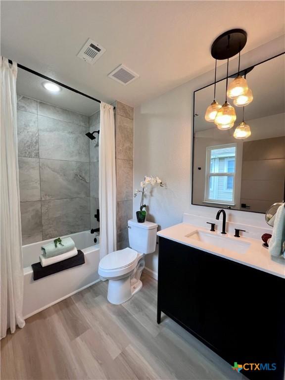 107 S 23rd St, Temple, TX 76504 - bathroom featuring toilet, wood finished floors, shower / tub combo, vanity, and baseboards