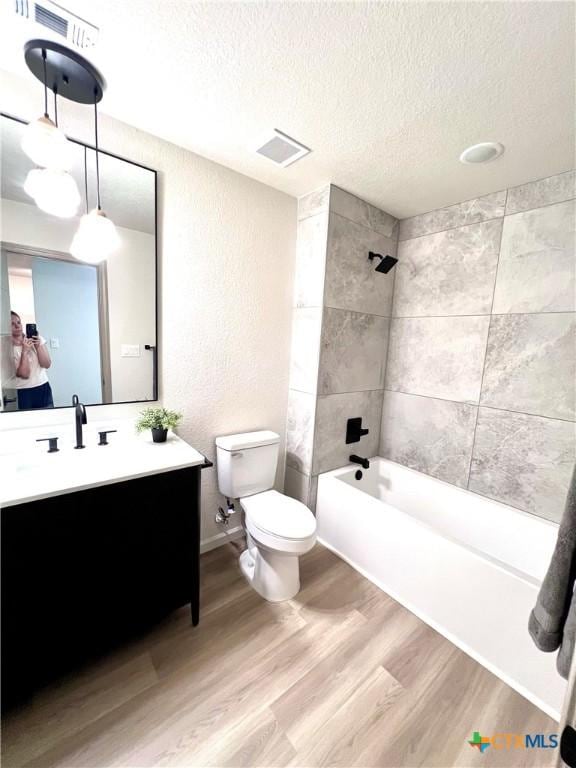 107 S 23rd St, Temple, TX 76504 - full bath with a textured ceiling, toilet, wood finished floors, vanity, and tub / shower combination