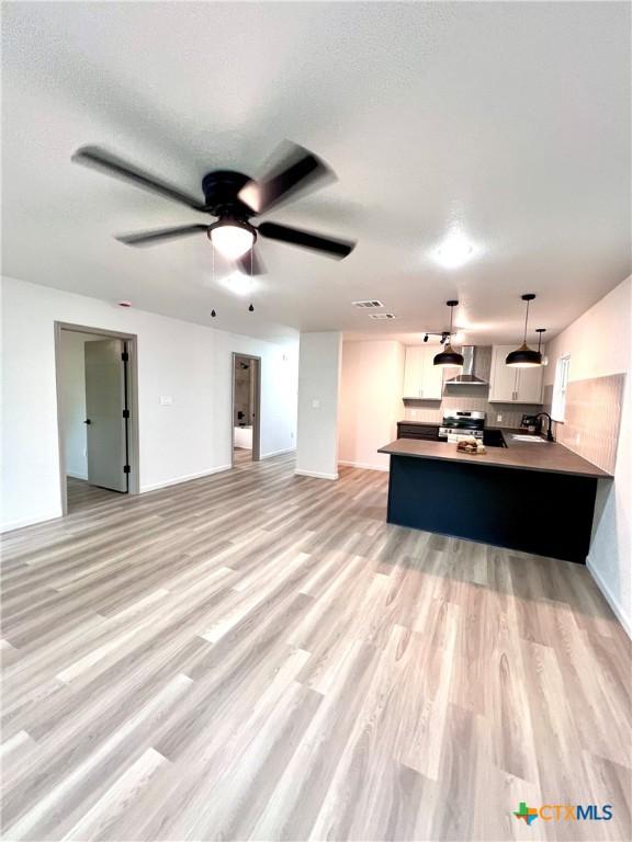 107 S 23rd St, Temple, TX 76504 - unfurnished living room with light wood-type flooring, a sink, ceiling fan, and baseboards