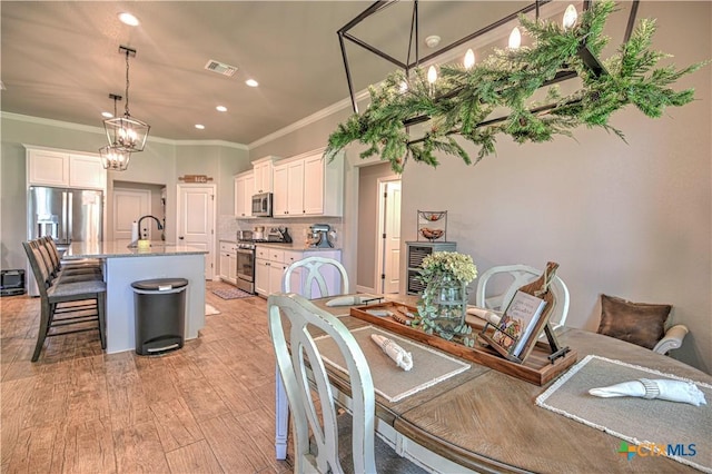 6129 Messina Dr, Temple, TX 76502 - dining area featuring crown molding, recessed lighting, light wood-style floors, and a chandelier