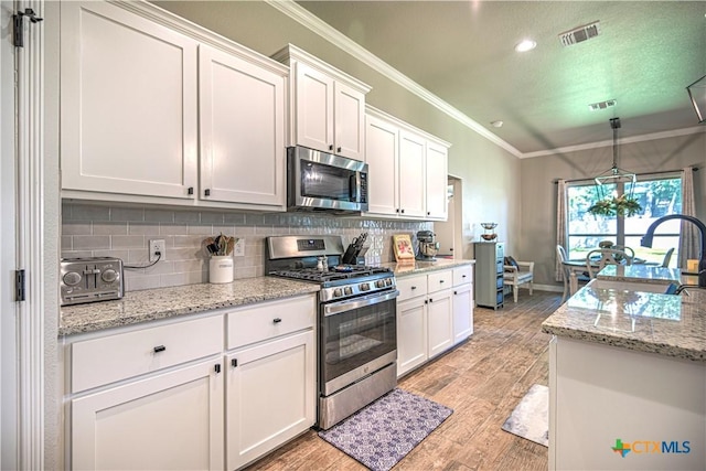 6129 Messina Dr, Temple, TX 76502 - kitchen with stainless steel appliances, crown molding, decorative backsplash, white cabinets, and light wood-style floors