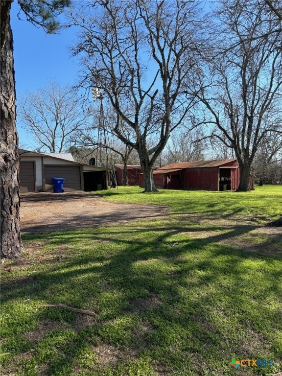 view of yard featuring a garage, a pole building, and an outbuilding