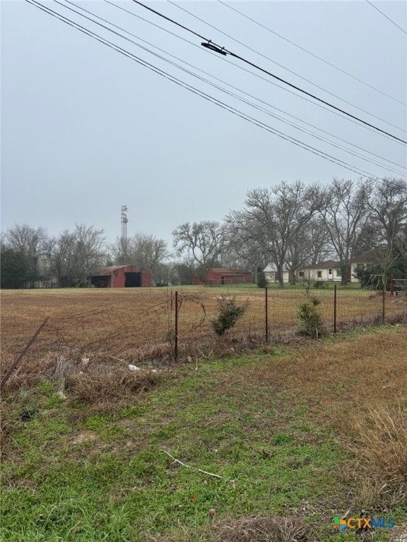 view of yard with a pole building, a rural view, fence, and an outdoor structure