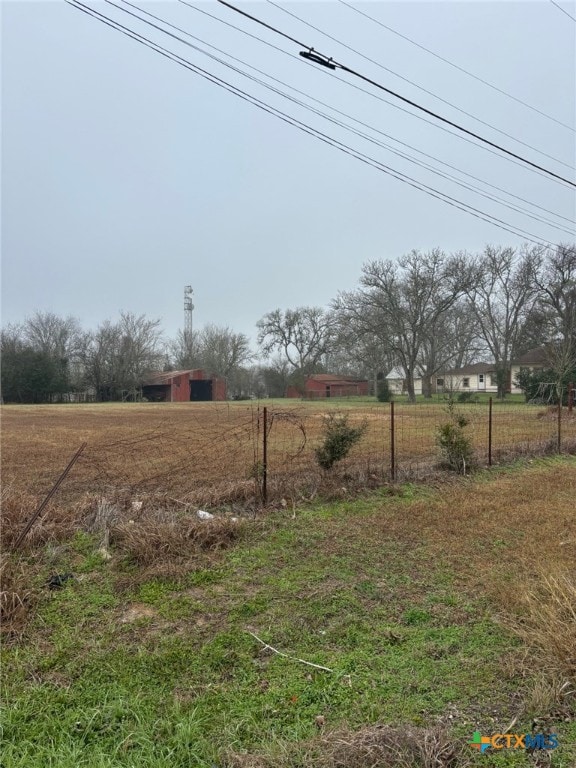 view of yard featuring an outbuilding, a rural view, an outdoor structure, and fence