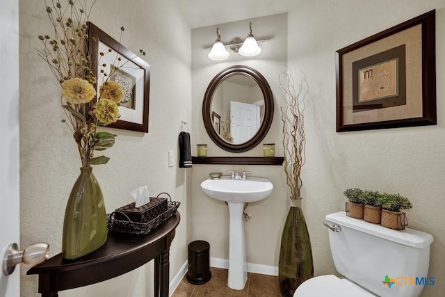 half bathroom with toilet, a sink, and tile patterned flooring