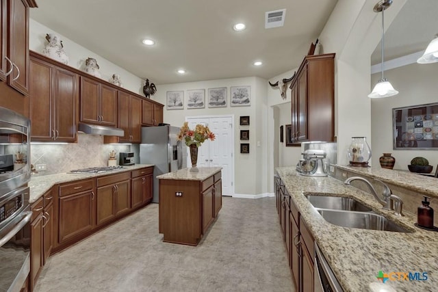kitchen with visible vents, appliances with stainless steel finishes, under cabinet range hood, a sink, and backsplash
