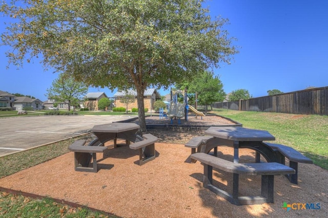 community play area featuring a yard and fence