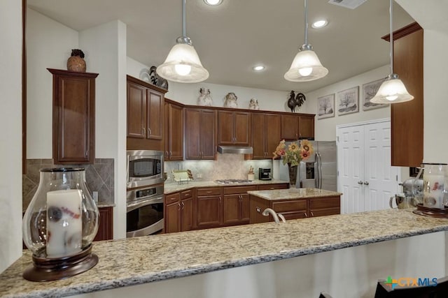 kitchen with appliances with stainless steel finishes, a peninsula, under cabinet range hood, decorative backsplash, and light stone counters