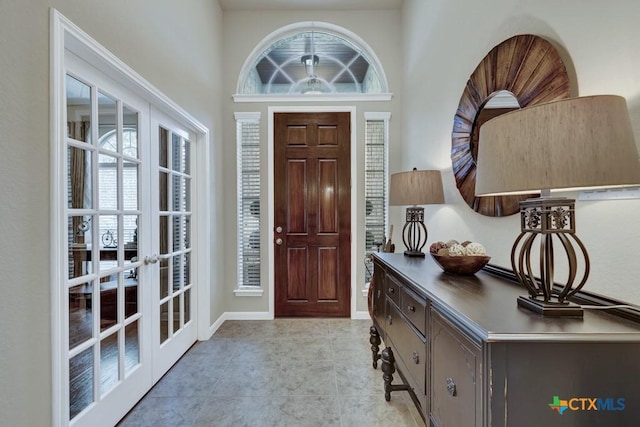 entrance foyer with french doors, baseboards, and a towering ceiling