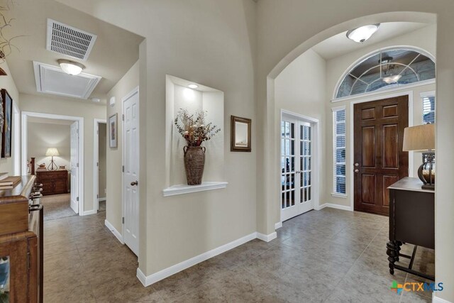 foyer entrance featuring arched walkways, baseboards, tile patterned flooring, and visible vents