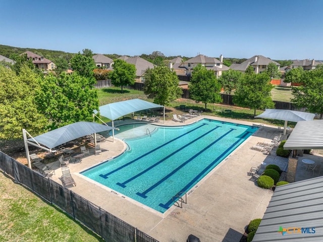community pool with fence, a patio, and a residential view