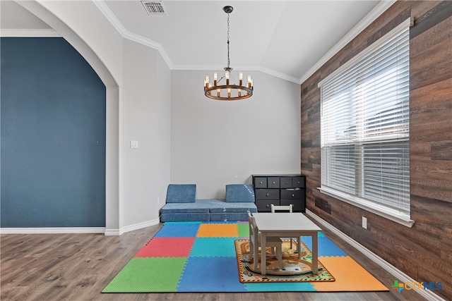 rec room featuring hardwood / wood-style floors, wood walls, an inviting chandelier, crown molding, and vaulted ceiling