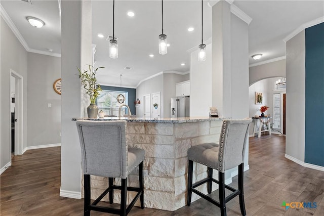 5502 Kent Dr, Belton, TX 76513 - kitchen with arched walkways, stainless steel fridge with ice dispenser, dark wood-style flooring, a kitchen bar, and ornamental molding