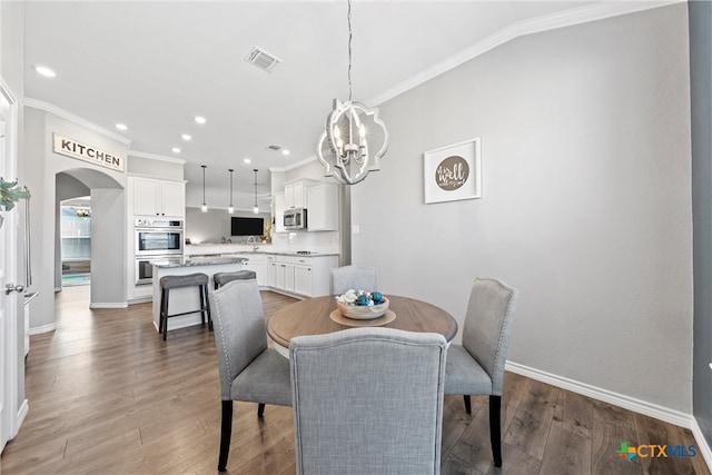 dining area featuring an inviting chandelier, ornamental molding, and hardwood / wood-style flooring