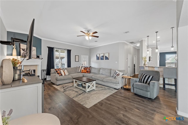 living room with ceiling fan, a fireplace, dark hardwood / wood-style flooring, and crown molding