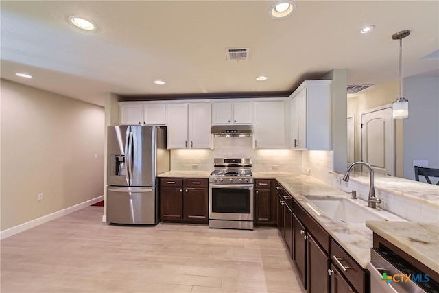 kitchen with pendant lighting, sink, stainless steel appliances, white cabinets, and decorative backsplash