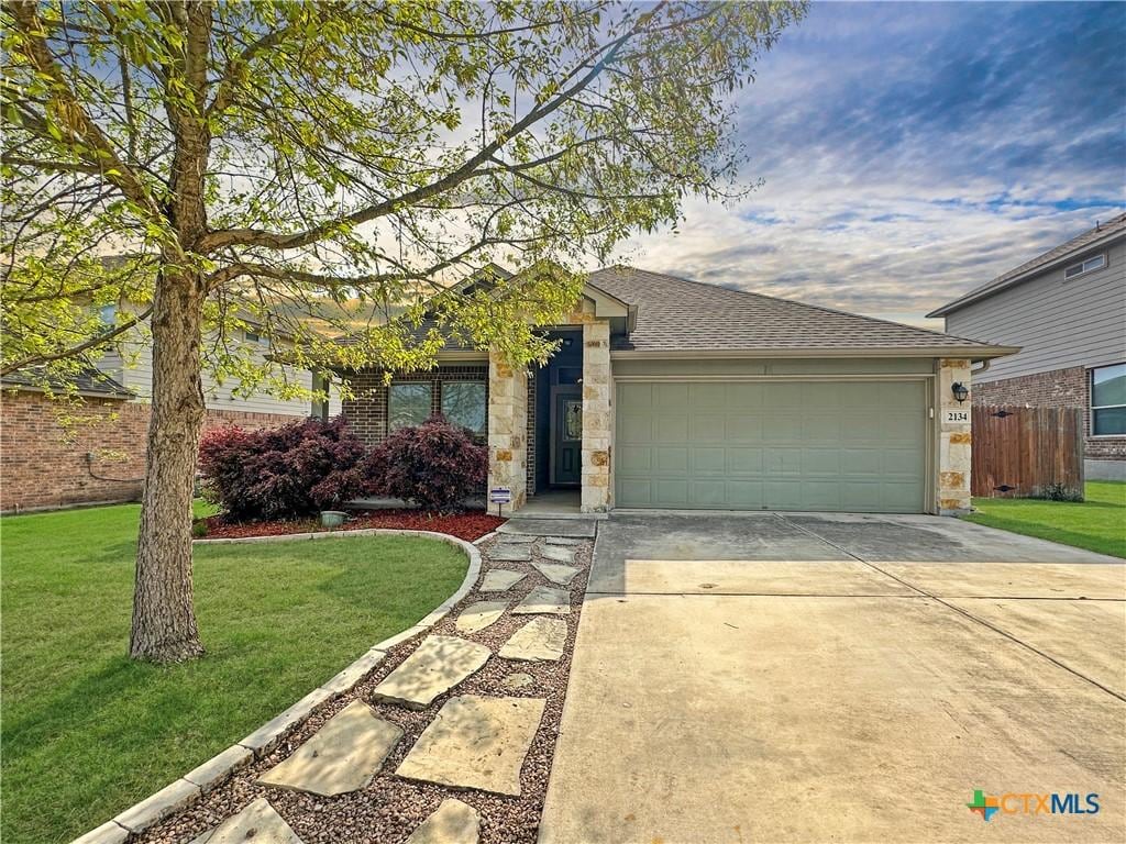 2134 Dove Crossing Dr, New Braunfels, TX 78130 - single story home with a garage, stone siding, a front lawn, a shingled roof, and concrete driveway